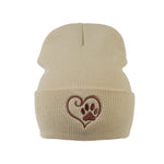 Beanie aus 100 % Acryl in beige mit Herz-Pfoten-Stickerei. Unisex, One Size.