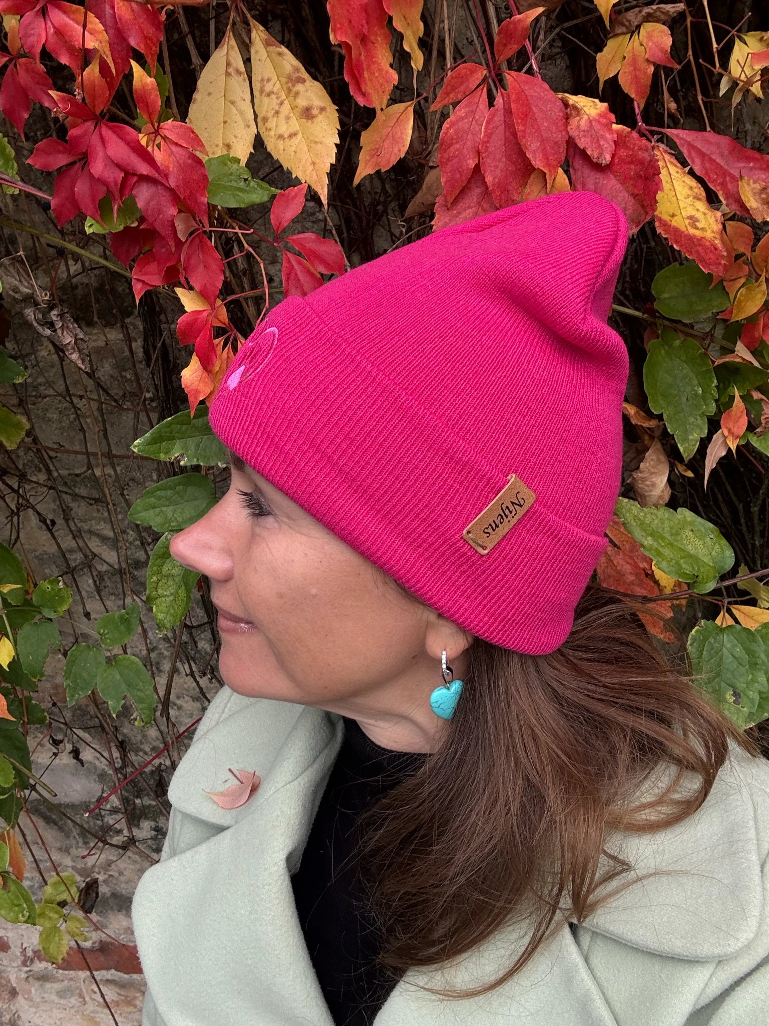 Frau trägt Fuchsia Beanie mit Pfote-&-Herz-Stickerei beim herbstlichen Spaziergang
