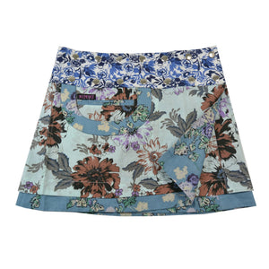 Kurzer Wenderock von Nijens mit hellblauem Grund und floralen Mustern in Braun, Lila und Creme – kombiniert mit dunkelblauem Bund in Kontrastoptik und kleiner Tasche.
