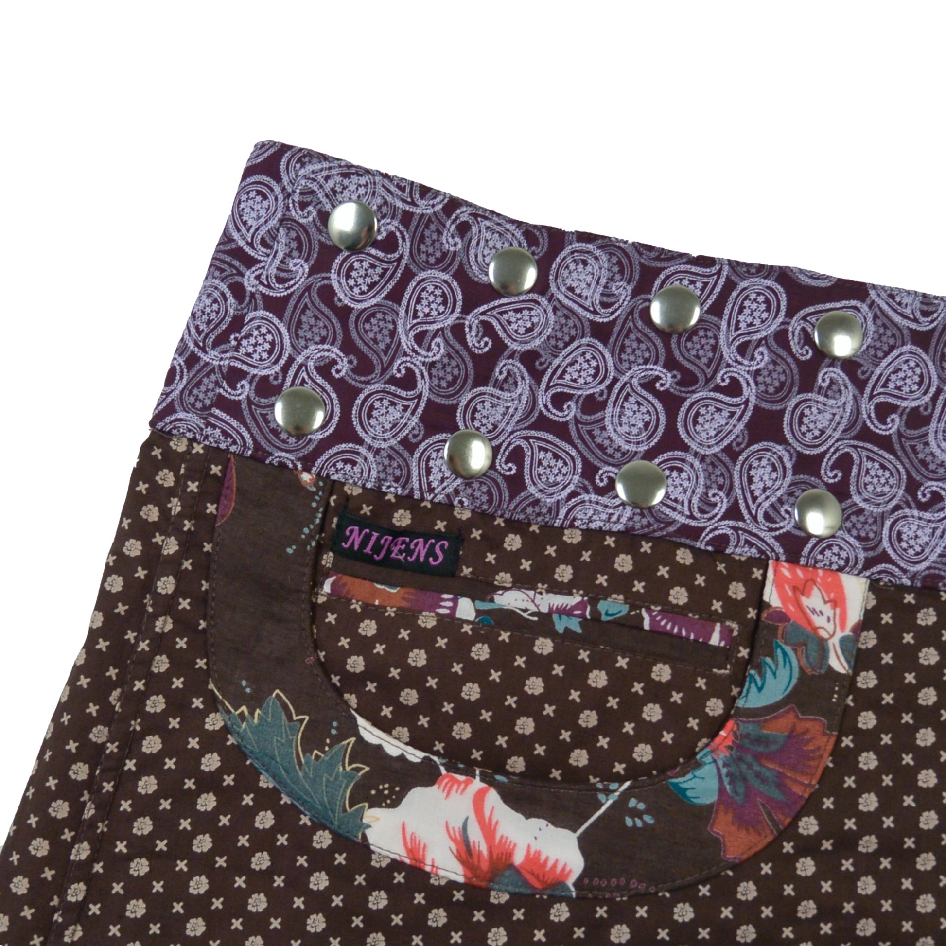 Detailansicht der Tasche und des lilafarbenen Paisley-Bundes mit silbernen Druckknöpfen – fein verarbeitet und stilvoll kombiniert.