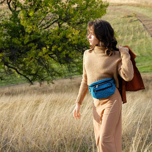 Eine Frau trägt die Hüfttasche aus Stoff Türkis mit Pfotenmuster
